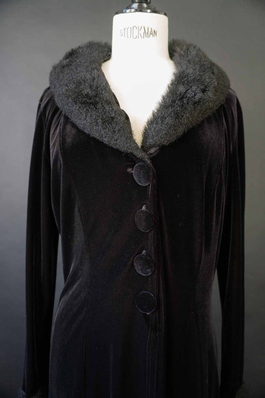 Langer schwarzer Vintage Samtmantel mit flauschigem Kragen und Manschetten in Felloptik, stoffbezogenen Knöpfen und Schlitz vorne und hinten – theplaincircle vintage