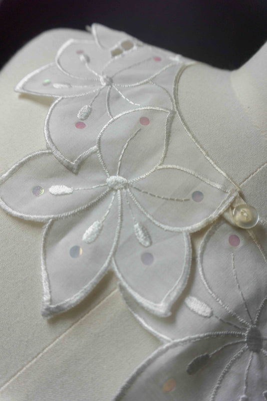 Weißer Krageneinsatz mit Blütenform und Pailletten, vorne geknöpft