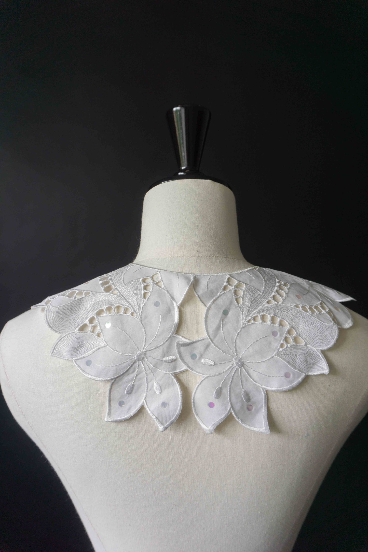 Weißer Krageneinsatz mit Blütenform und Pailletten, vorne geknöpft