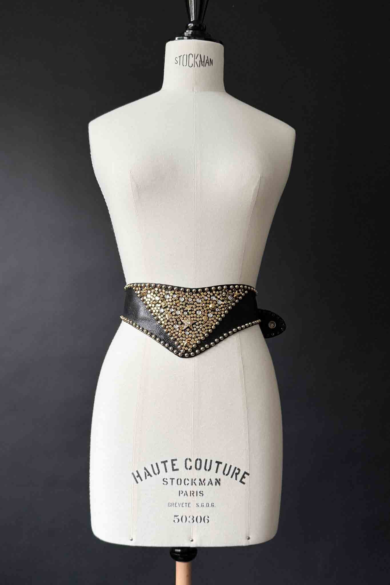 Breiter schwarzer Kolster Ledergürtel mit goldenen Nieten und dreieckigem Frontpanel.