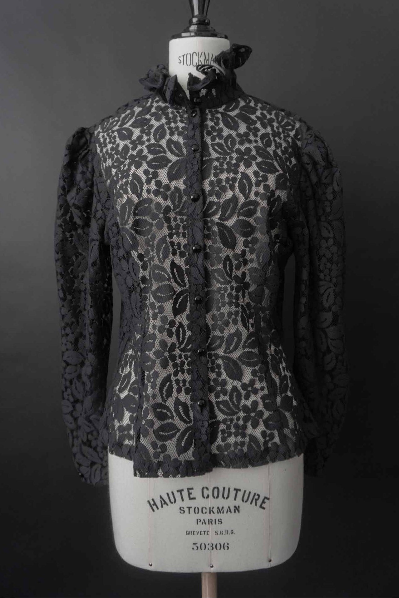 Schwarze transparente Vintage Spitzenbluse aus den 1980er Jahren mit Stehkragen, Volantdetails und floralem Spitzenmuster.
