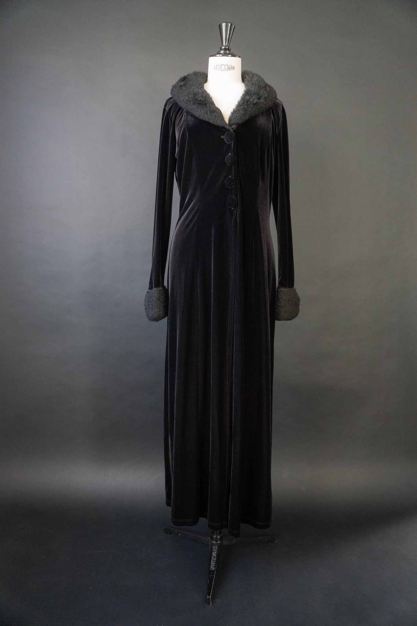 Langer schwarzer Vintage Samtmantel mit flauschigem Kragen und Manschetten in Felloptik, stoffbezogenen Knöpfen und Schlitz vorne und hinten – theplaincircle vintage