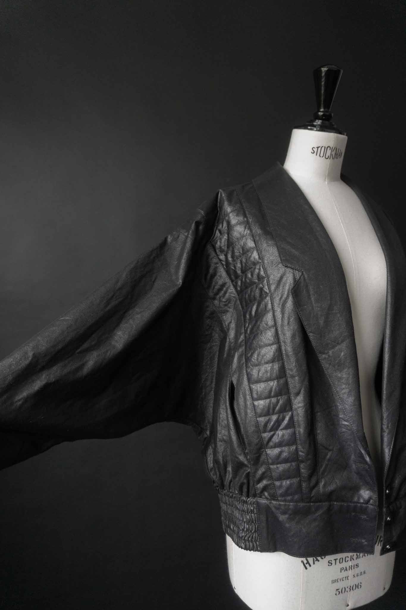 Schwarze Vintage Blousonjacke mit Steppnähten und Fledermausärmeln auf schwarzem Hintergrund