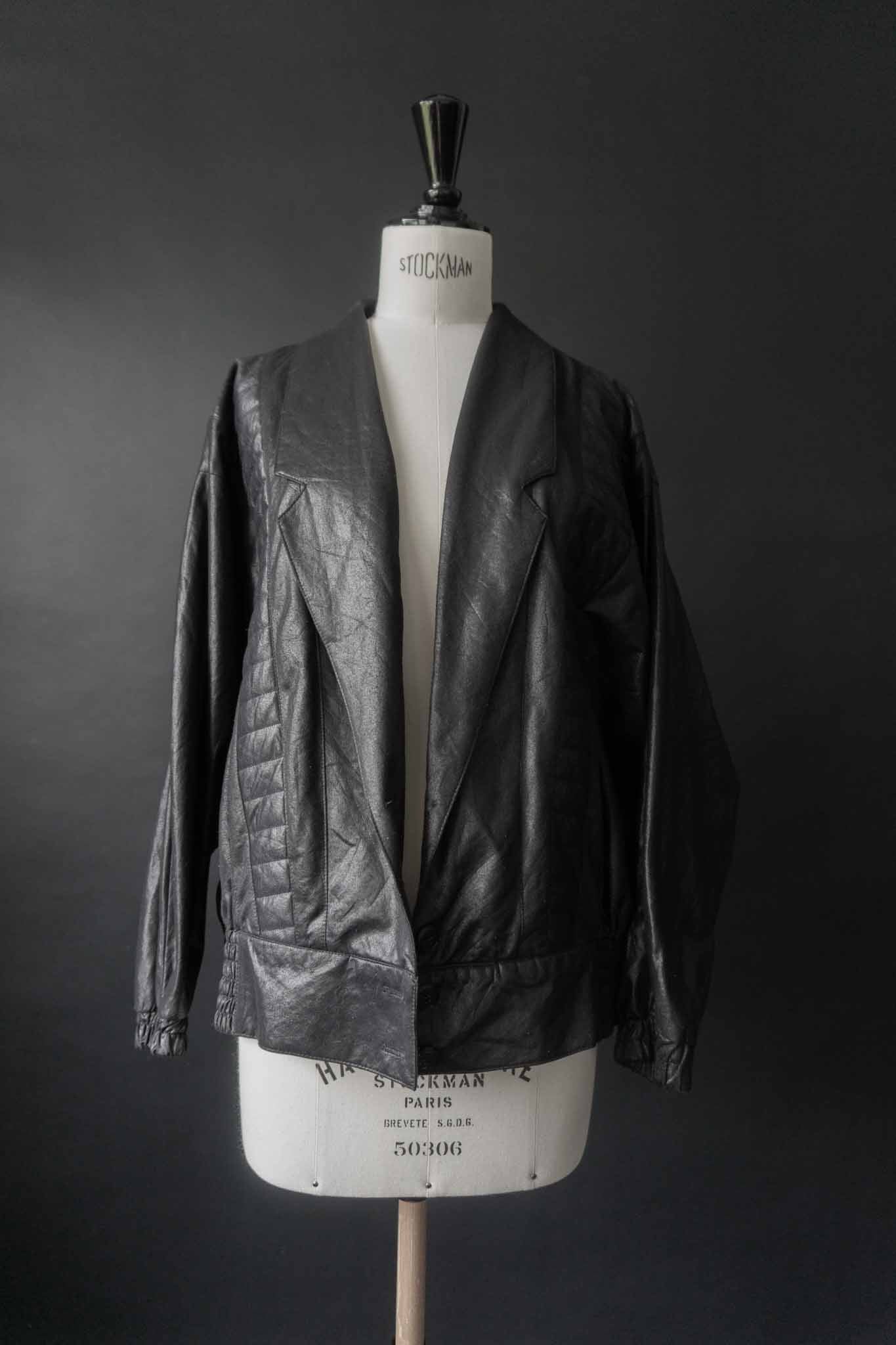 Schwarze Vintage Blousonjacke mit Steppnähten und Fledermausärmeln auf schwarzem Hintergrund