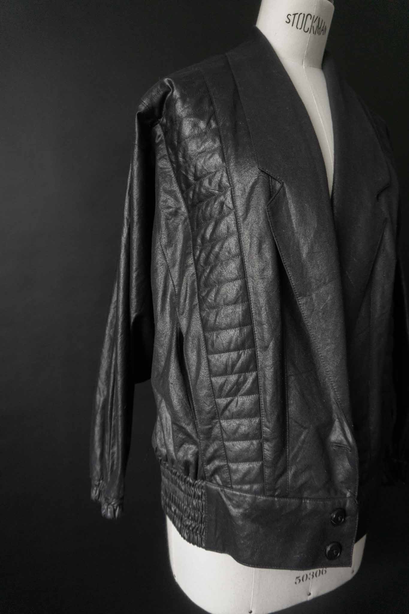 Schwarze Vintage Blousonjacke mit Steppnähten und Fledermausärmeln auf schwarzem Hintergrund