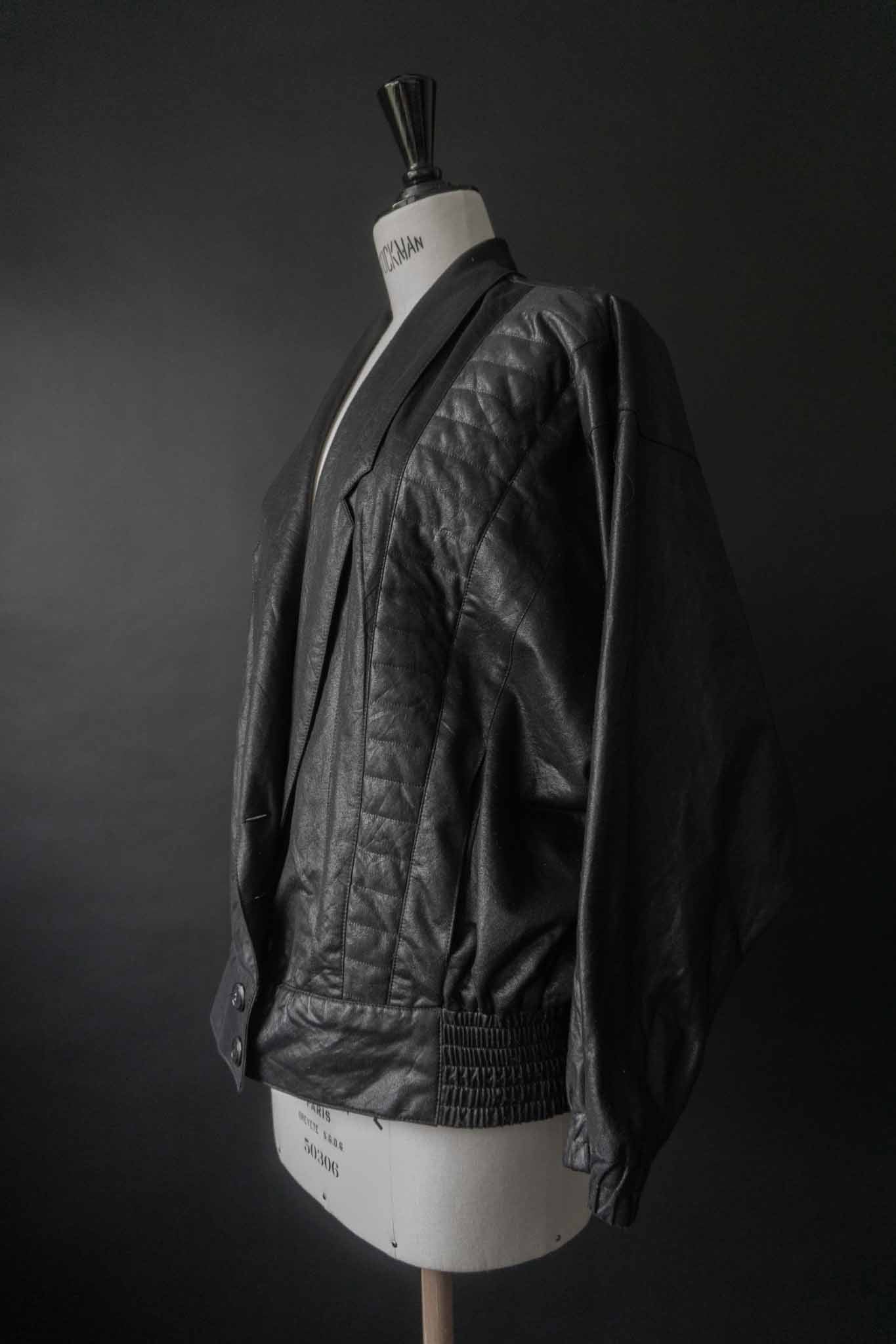 Schwarze Vintage Blousonjacke mit Steppnähten und Fledermausärmeln auf schwarzem Hintergrund