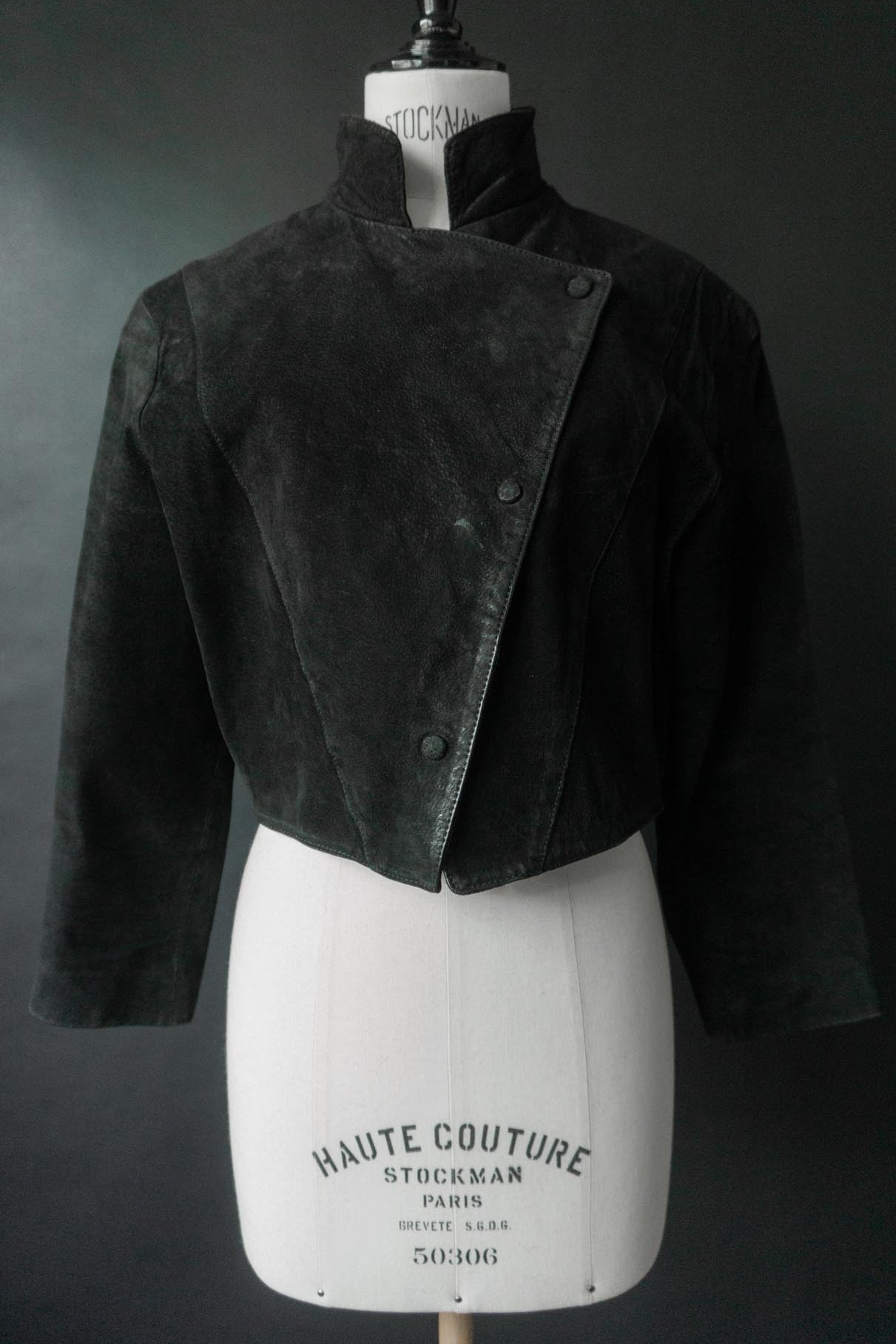 Schwarze 80er Wildlederjacke mit asymmetrischem Druckknopfverschluss und skulpturalem cropped Schnitt.