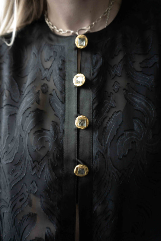 Schwarze transparente Bluse mit floralen Ranken und goldenen Schmuckknöpfen