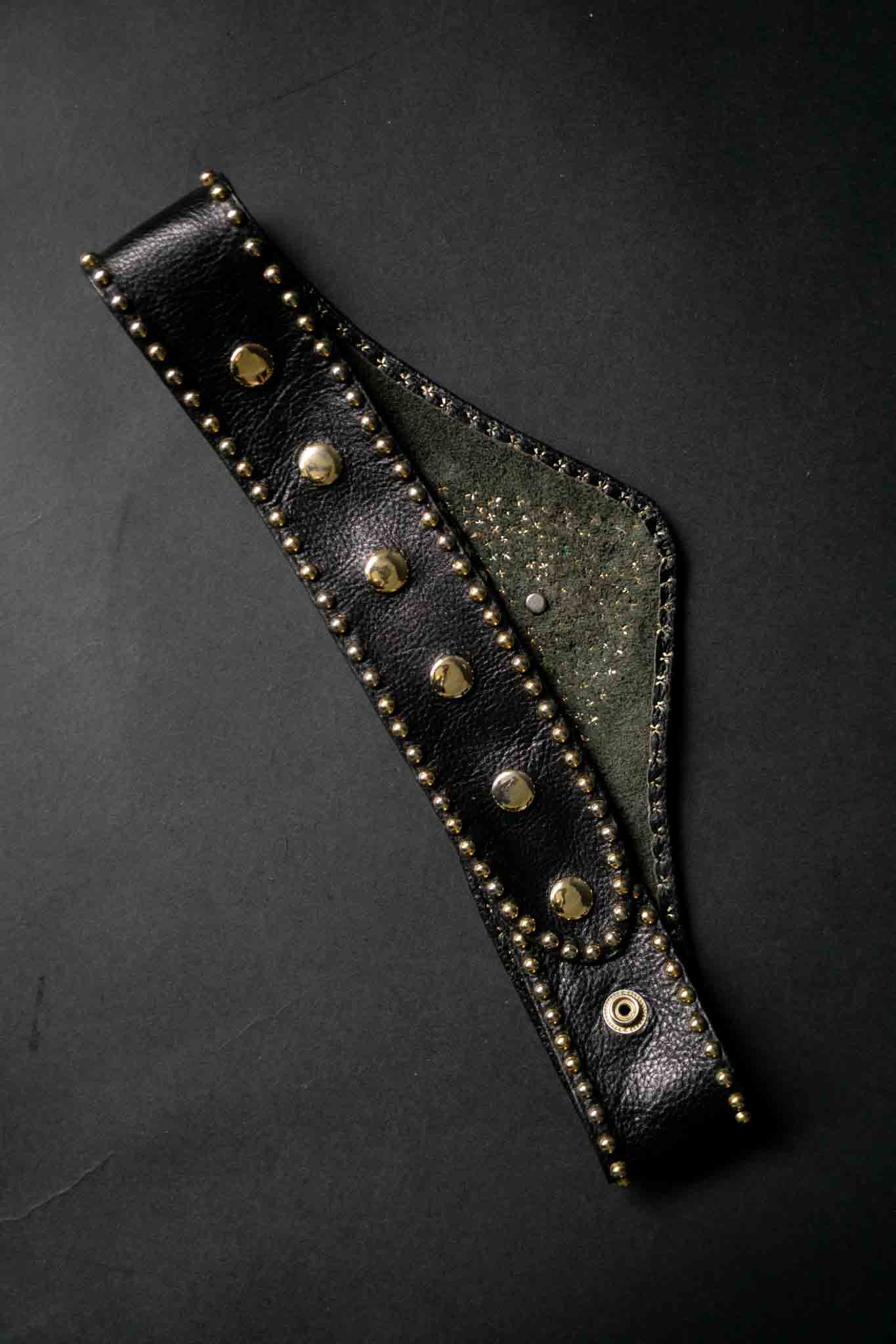 Breiter schwarzer Kolster Ledergürtel mit goldenen Nieten und dreieckigem Frontpanel.