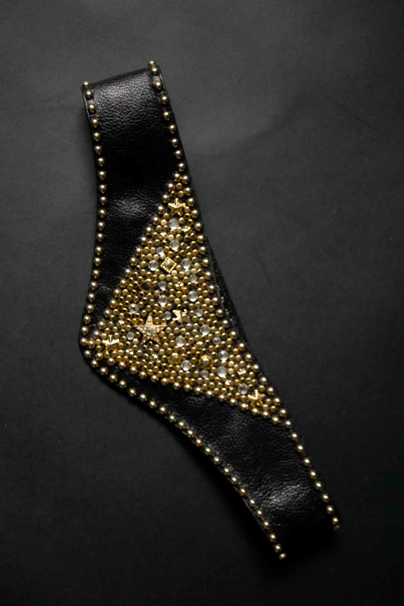 Breiter schwarzer Kolster Ledergürtel mit goldenen Nieten und dreieckigem Frontpanel.